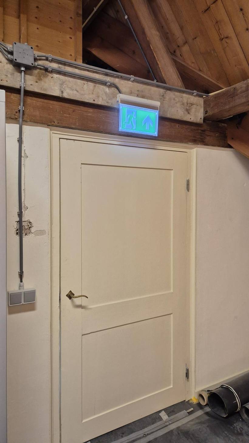 Noodverlichting en vluchtwegaanduiding boven de doorgang